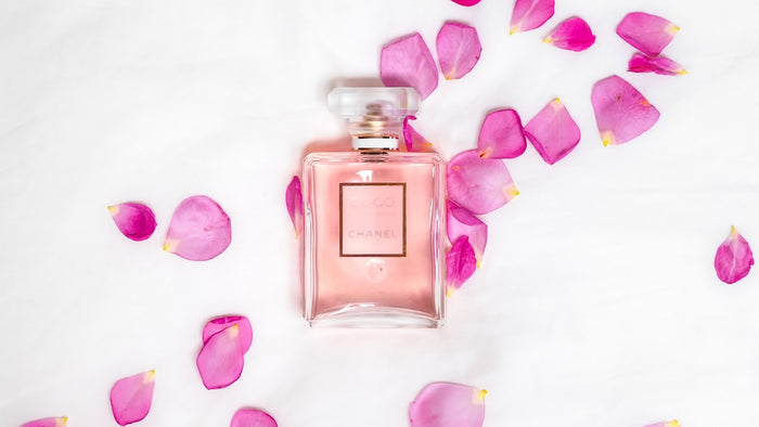 Perfume bottle resting among pink petals