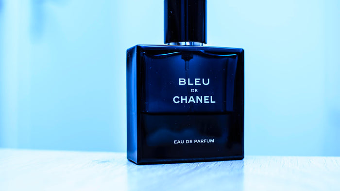 Blue glass designer fragrance bottle on a plain background